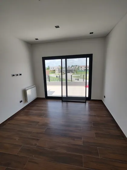 Living moderno con piso de madera oscura y ventanales amplios — proyecto Casa En El Barrio De Los Talas, por Ves Arquitectura , en Canning